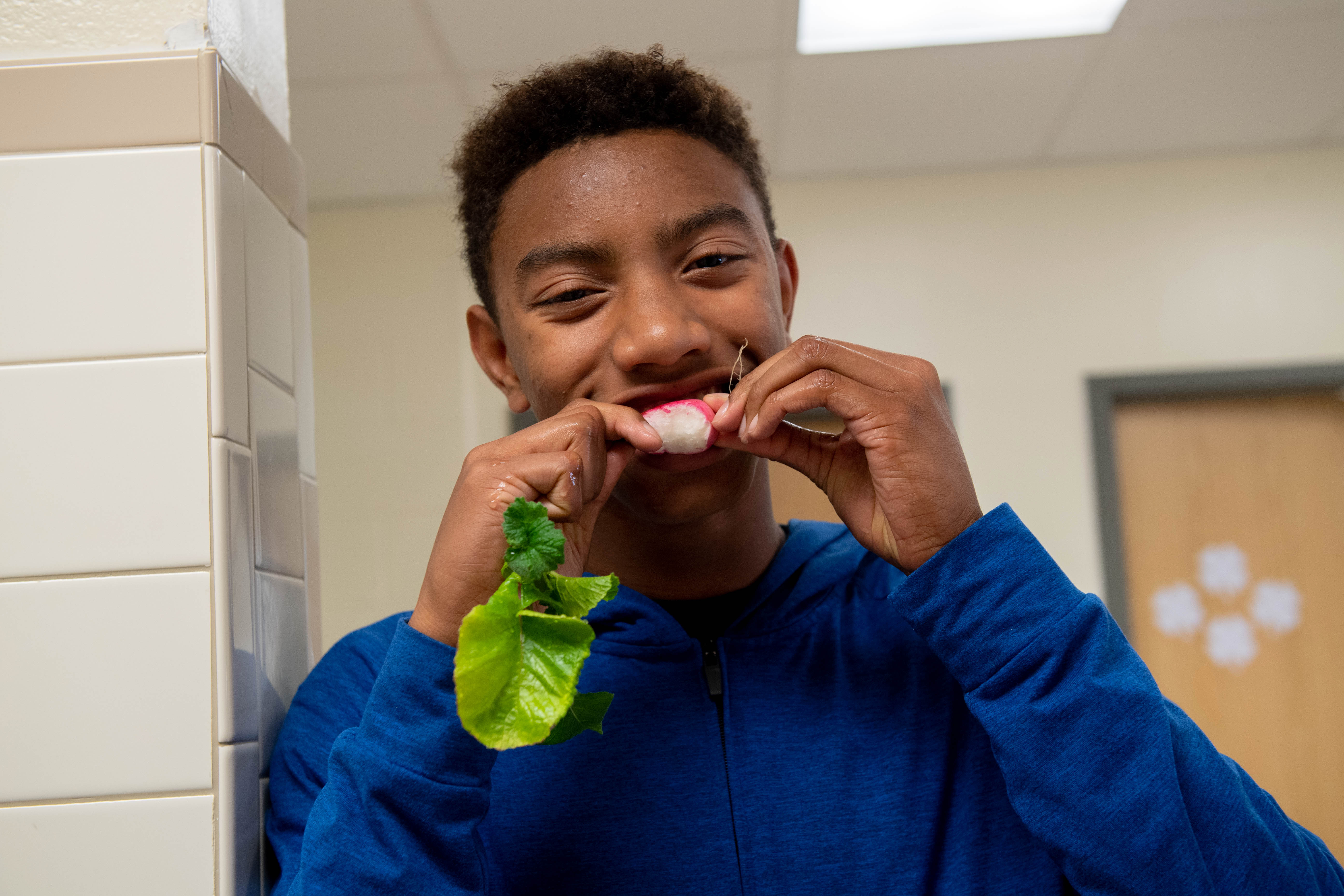 Edison student Jalani Marshall samples a radish grown in his group's vertical farming unit.